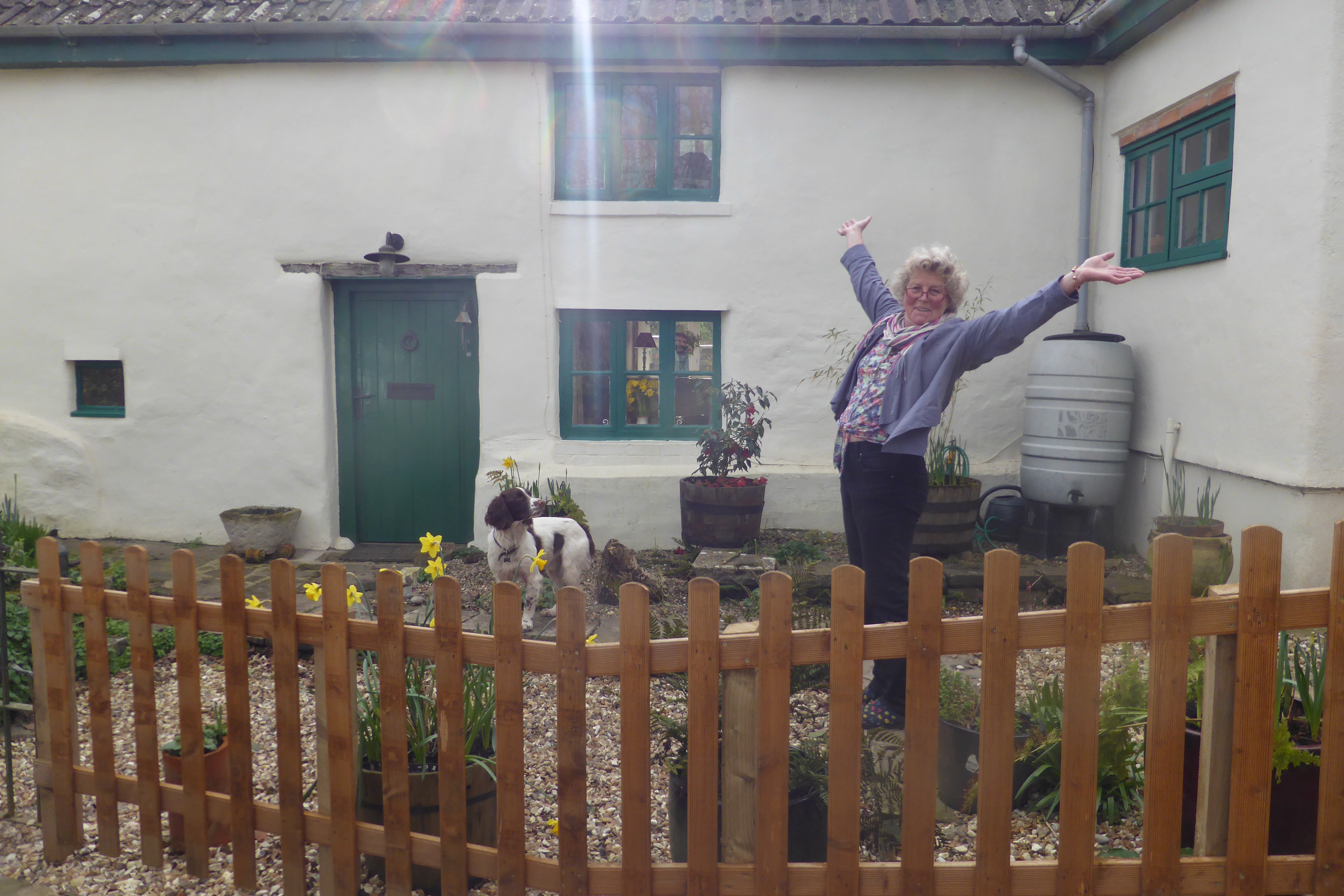 Image-of-a-happy-customer-Nikki-standing-by-the-discreet-high-quality-below-ground-WPL-Diamond-package-wastewater-sewage-treatment-pant-for-off-mains-drainage- at-a-beautiful-cottage-in-the-uk-the-wpl-diamond-replaced-a-leaking-septic-tank.